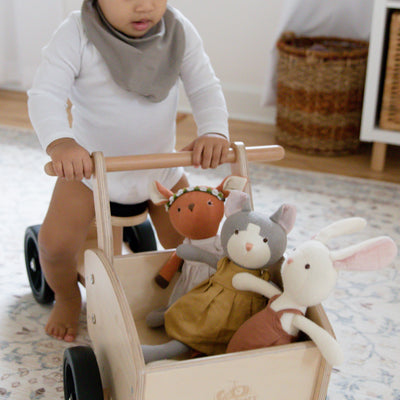 Little boy pushing toy cart with stuffed animals