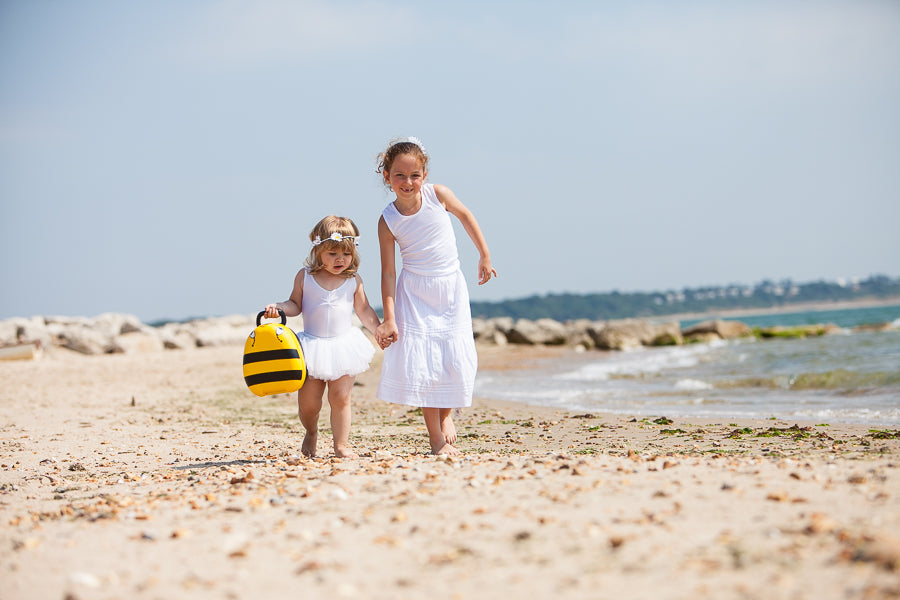 Sisters walking along the beach carrying a potty