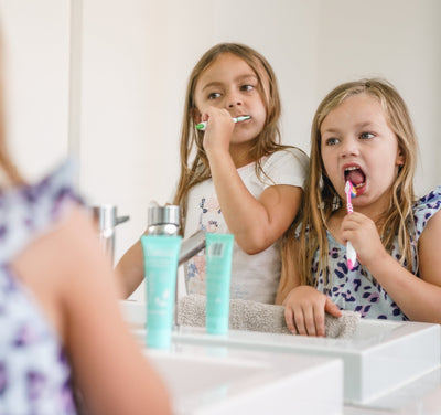 Girls brushing their teeth in the mirror
