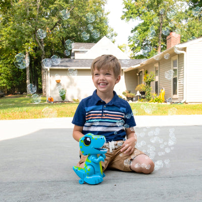 Child playing with a a blue dinosaur toy with bubbles in a backyard setting