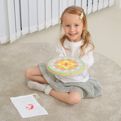 Young girl holding a colorful wooden toy on a carpeted floor.