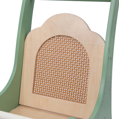 Close-up of a doll high chair with a green frame and beige backrest with wicker design.
