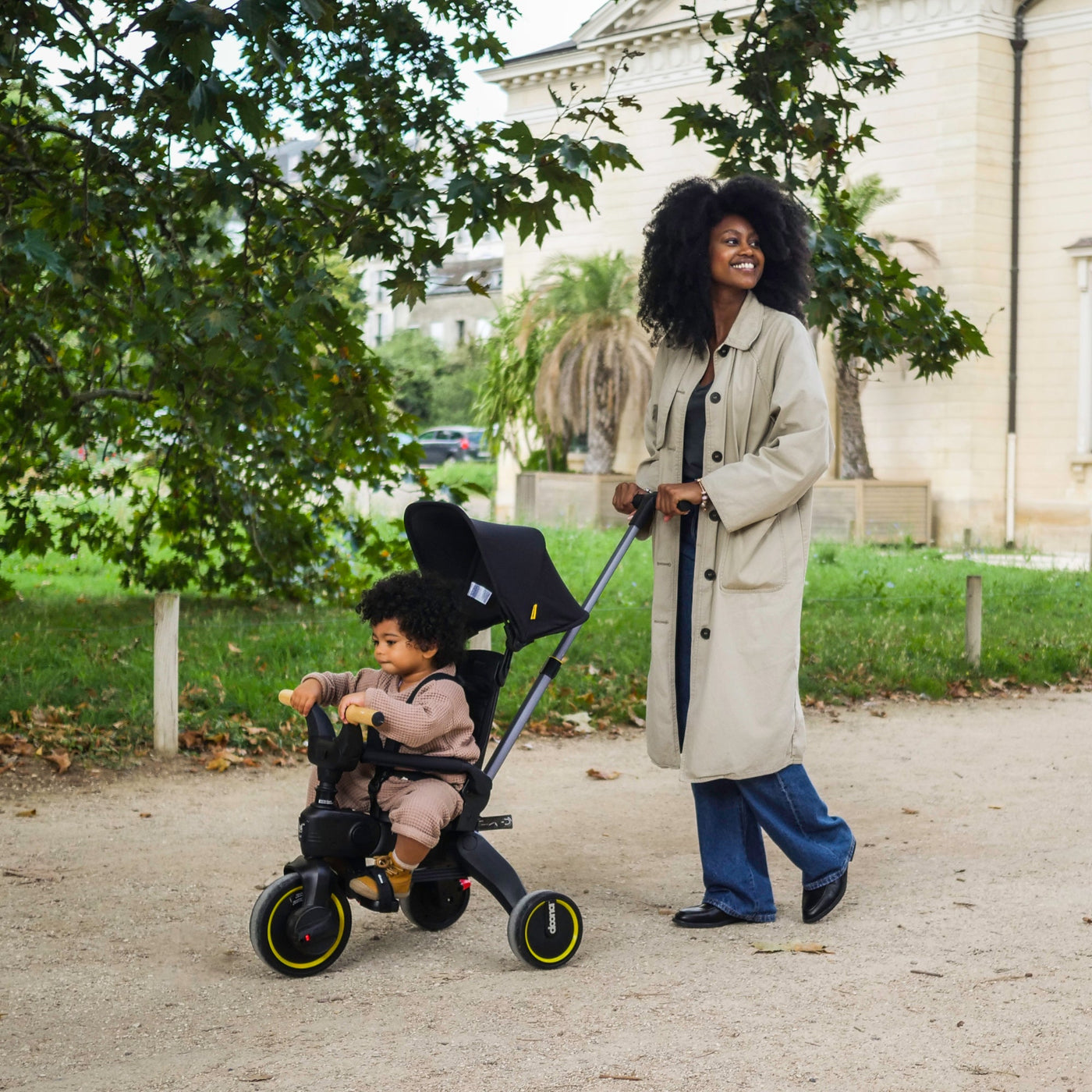 Woman pushing a child in a stroller in a park-like setting