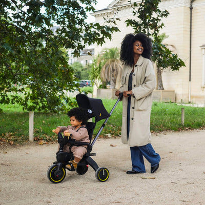 Woman pushing a child in a stroller in a park-like setting