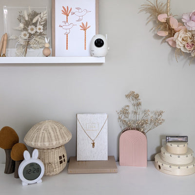 Decorative items on a shelf including a mushroom-shaped lamp, a clock, and a vase with dried flowers.